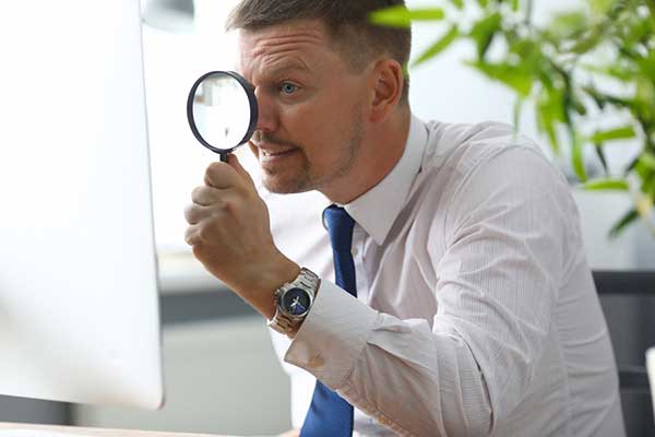 man looking at a computer screen with a magnifying glass