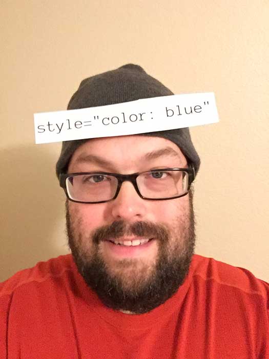 Justin Stockton wearing a green beanie with a note on it saying “style = color: blue”.