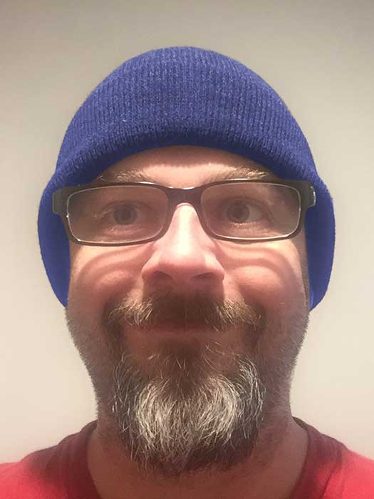 Karl Groves wearing a blue beanie and unsettling smile.