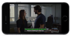 A TV show on an iOS device showing two people speaking. CC are color coded for each person