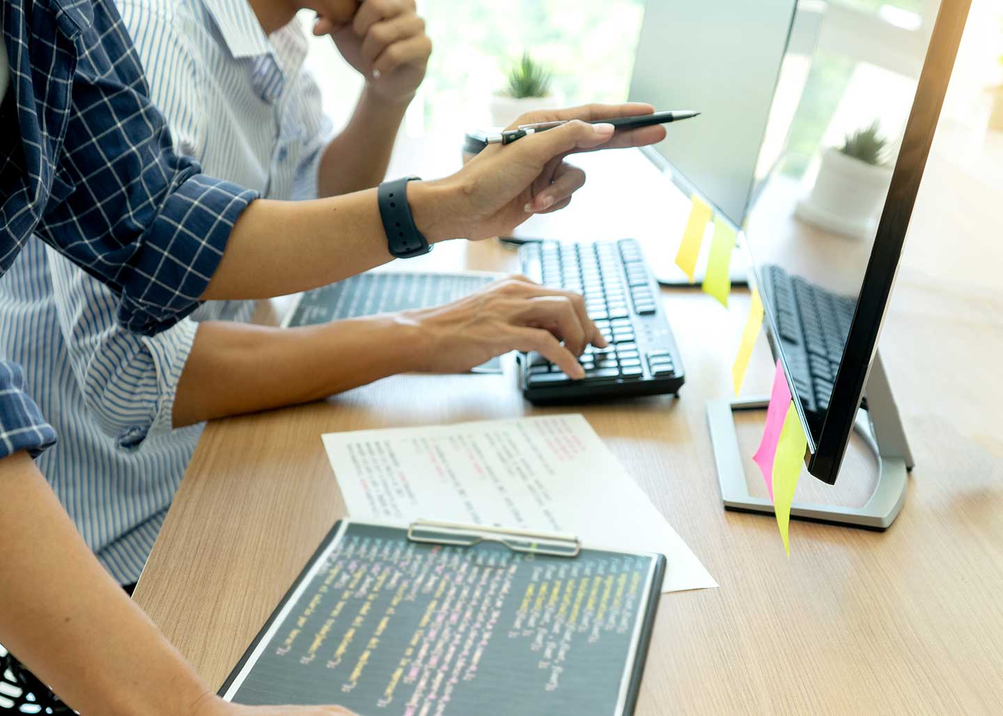 Two people in front of a desk review information on a computer monitor