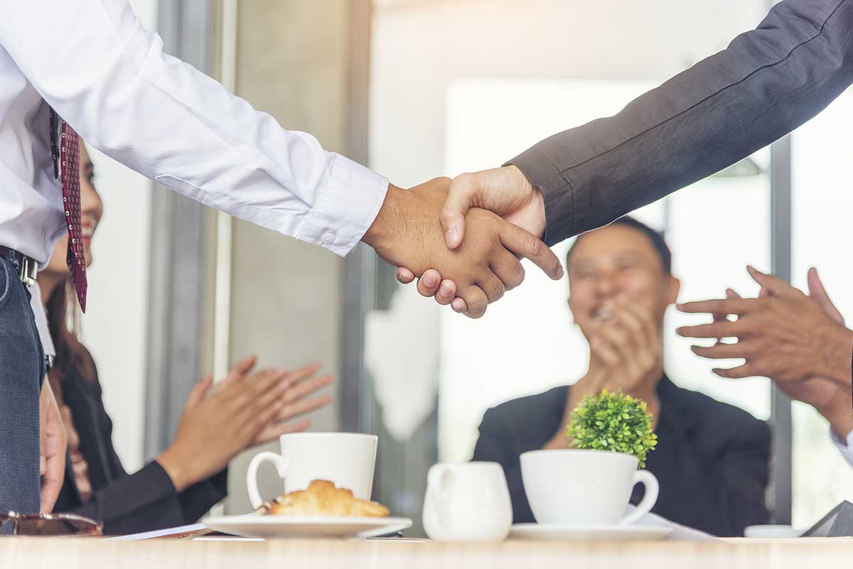Close-up of two people shaking hands across a table