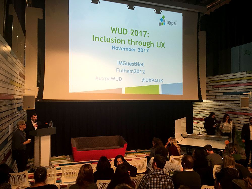 Photograph of the UXPA event venue, showing "WUD 2017: Inclusion through UX" slide