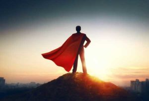 the back view of a man wearing a suit that has a red cape, looking over a city