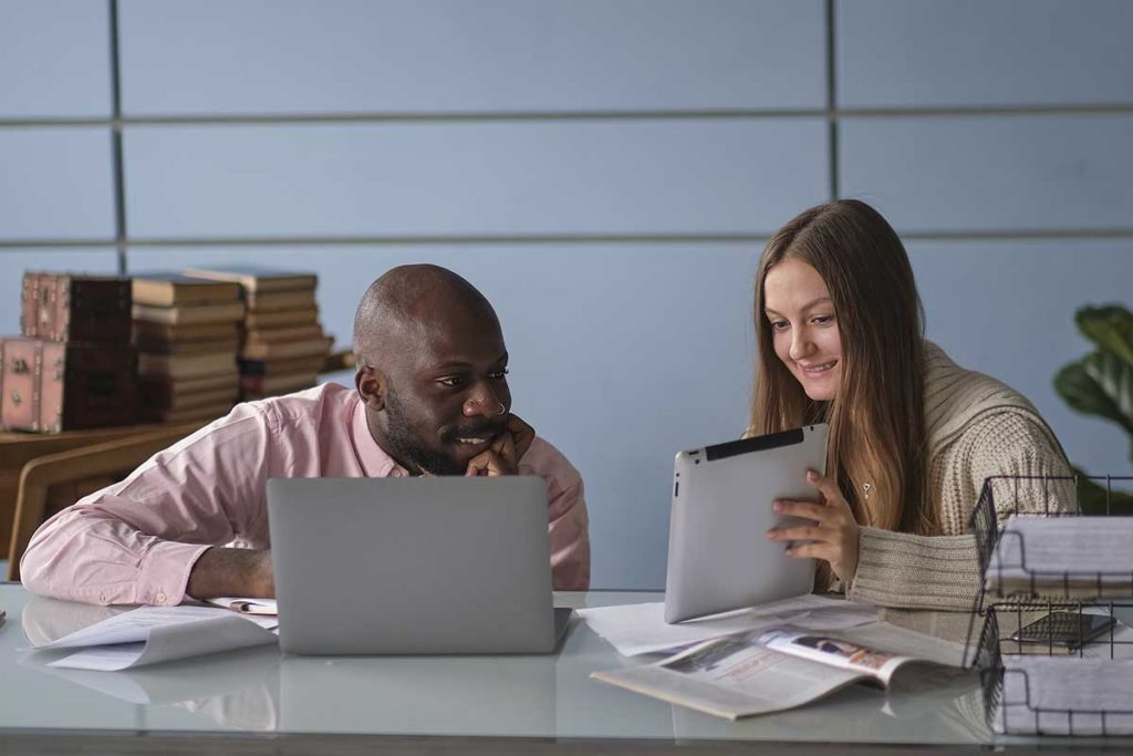 a man and a woman at a desk, collaborating on a work project
